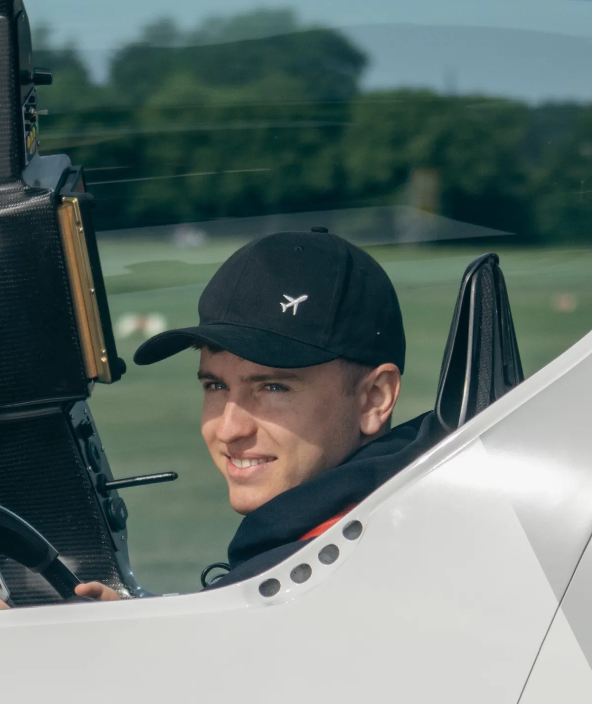 Lachender Pilot mit Kappe im offenen Cockpit